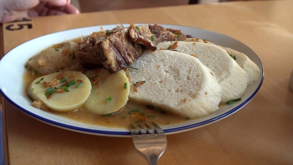 saftiger Schweinebraten, der an traditionellem Kraut und zweierlei Knödeln